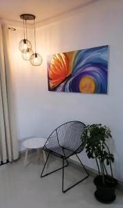 una silla y una planta en una habitación con una pintura en Cabañas Mantas, en Tarcoles