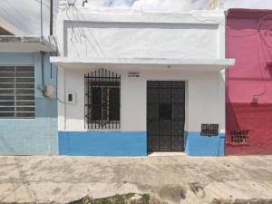 Una casa blanca y azul con una puerta. en Pequeña casa en el centro de Mérida en Azcorra