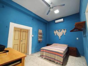 - une chambre bleue avec un lit et un ventilateur de plafond dans l'établissement Pequeña casa en el centro de Mérida, à Azcorra