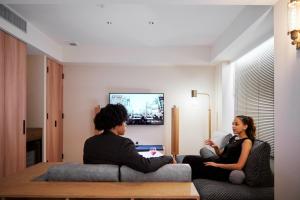 un uomo e una donna seduti su un divano in un soggiorno di NOHGA HOTEL AKIHABARA TOKYO a Tokyo