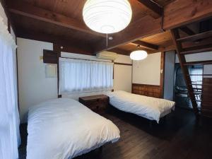 una camera da letto con due letti e un lampadario di 日々の宿しののめ101 宇野駅から車で5分 直島へ 最大8名様 古民家 a Tamano