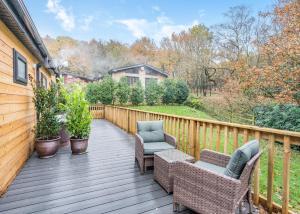 a wooden deck with two chairs and chairs on it at Charlesworth Lodges in Glossop