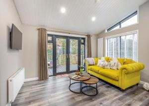 a living room with a yellow couch and a table at Charlesworth Lodges in Glossop