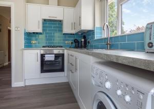 una cocina con armarios blancos y azulejos azules en Lee Valley en Hoddesdon