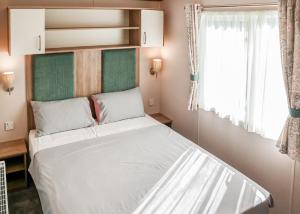 a small bedroom with a bed and a window at Golden Palm Resort in Chapel Saint Leonards