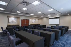 a conference room with tables and chairs and a screen at Courtyard Austin Airport in Austin