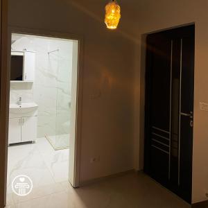 uma casa de banho com um chuveiro e uma porta de vidro em Eros Apartments em Pristina