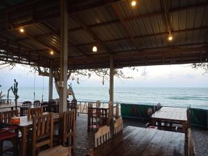 um restaurante na praia com mesas e cadeiras em HOME NO 3 khanom em Ban Thung O