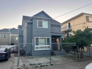 uma casa cinzenta com uma vedação à frente. em Charming Victorian Vacation Rental - Walking Distance BART em Oakland