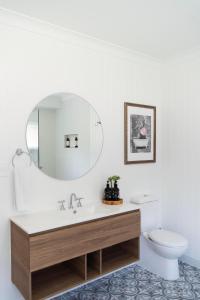 a bathroom with a sink and a toilet and a mirror at Lazy Frog Lodge Mudgee country luxury in Mudgee