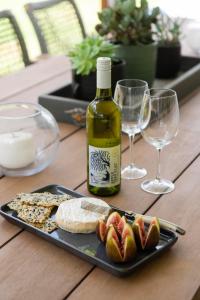 a bottle of wine and a plate of cheese and wine glasses at Lazy Frog Lodge Mudgee country luxury in Mudgee