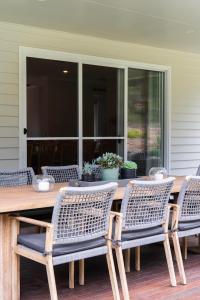 a wooden table with four chairs on a porch at Lazy Frog Lodge Mudgee country luxury in Mudgee