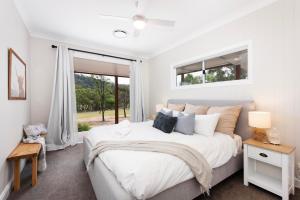 a white bedroom with a large bed and a window at Lazy Frog Lodge Mudgee country luxury in Mudgee