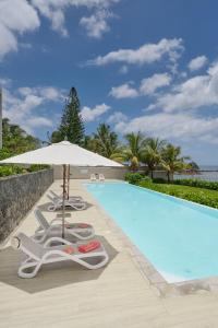 een zwembad met 2 ligstoelen en een parasol bij Otera 2 Penthouse with panoramic view by LOV in Trou aux Biches