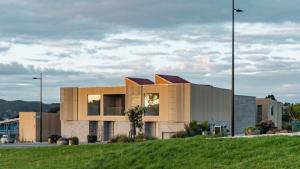 a building with a grassy field in front of it at Raglan Dreams in Raglan