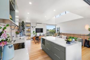 a kitchen and living room with white walls and wood floors at Raglan Dreams in Raglan