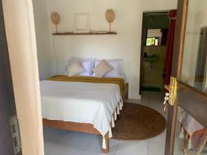 Schlafzimmer mit einem Bett mit weißer Bettwäsche und blauen Kissen in der Unterkunft Keladi Villa in Gili Trawangan