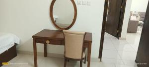 a dressing table with a mirror and a chair at فندق رفال الغربية للشقق المخدومة in Ukaz