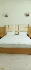 a bed with a wooden frame and white sheets at فندق رفال الغربية للشقق المخدومة in Ukaz