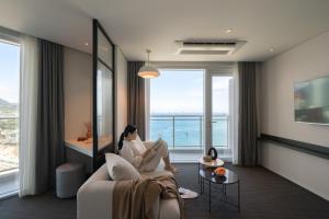 a woman sitting on a couch in a room with a window at Urbanstay Busan songdo Beach in Busan