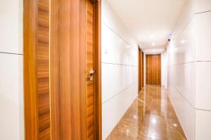 a hallway with white walls and a wooden door at FabHotel Shubham Inn in Mumbai