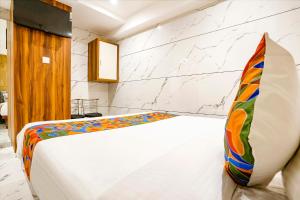 a bedroom with a white bed with a colorful pillow at FabHotel Shubham Inn in Mumbai