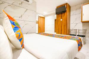 a bedroom with a white bed with a colorful pillow at FabHotel Shubham Inn in Mumbai