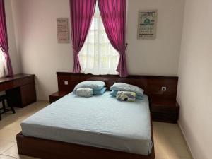 a bedroom with a bed with two pillows and a window at Rumah Singgah Taman Belia Antarabangsa in Ayer Keroh