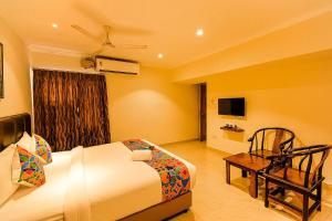Habitación con cama, sofá y TV. en Blossoms Hotel & Service Apartments, en Chennai