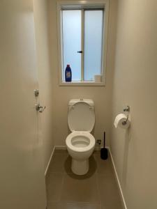 a bathroom with a toilet with a window at Comfy Newly Furnished Queen bedroom in Point Cook