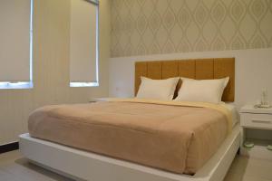 a bedroom with a large bed with a wooden headboard at GRAND DARUSSALAM HOTEL in Medan