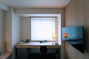 a room with a desk with a window and a monitor at KOKO HOTEL Sendai Kotodai Park in Sendai