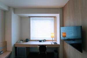 Habitación con escritorio, ventana y monitor. en KOKO HOTEL Sendai Kotodai Park en Sendai