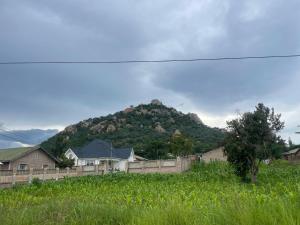 a house in a field with a mountain in the background at Rockville Abode in Iringa