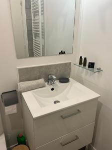 La salle de bains est pourvue d'un lavabo blanc et d'un miroir. dans l'établissement Vivez La vue mer - Studio - Port de plaisance - Plage, au Havre
