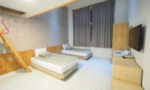 a bedroom with two beds and a flat screen tv at Aurora Hotel in Jeju