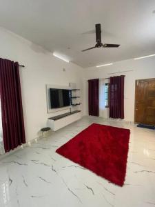 a living room with a red rug and a flat screen tv at Vacation Guest House in Trivandrum