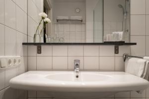 a white bathroom with a sink and a mirror at Hotel Au Quartier in Maastricht