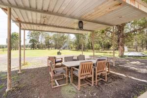 a table and chairs under a wooden pergola at NEW! Charming & Spacious 4BR Retreat in Pitt Town 