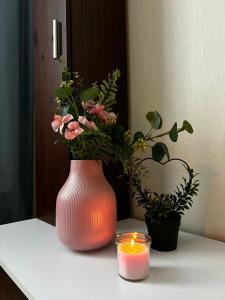 un jarrón rosa con flores y una vela sobre una mesa en Mammaste Apartment, en Mammaste