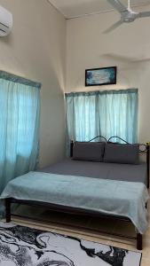 Cama grande en habitación con cortinas azules en Homestay MYZARAH en Pasir Puteh