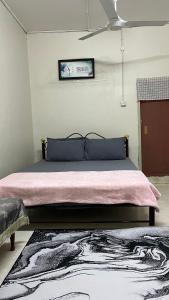 1 dormitorio con 1 cama con manta rosa y alfombra en Homestay MYZARAH en Pasir Puteh