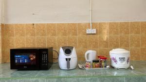 encimera de cocina con microondas y otros electrodomésticos en Homestay MYZARAH en Pasir Puteh
