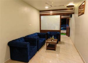 a living room with blue couches and a coffee table at Shrinidhi Residency Pune in Pune