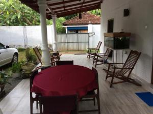 a patio with a table and chairs and a tv at Fern Dale in Weligama