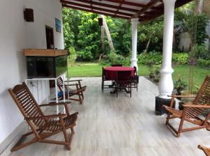 a patio with rocking chairs and a table and a fireplace at Fern Dale in Weligama