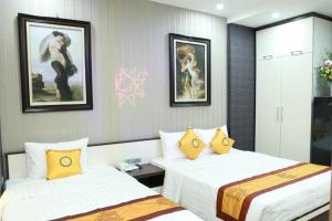 ein Hotelzimmer mit 2 Betten und Gemälden an der Wand in der Unterkunft My House Hotel - 350 Trần Khát Chân - by Bay Luxury in Hanoi