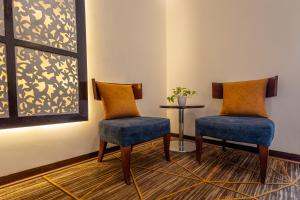 2 sillas en una habitación con mesa y ventana en Hotel 91 Golf Course Road, en Gurgaon