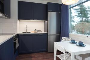 Easypass Apartmenthotel في هلسنكي: مطبخ مع دواليب زرقاء داكنة وطاولة بيضاء
