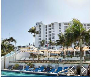 une piscine avec des chaises et des parasols et un hôtel dans l'établissement Breakers Resort, Umhlanga, à Durban